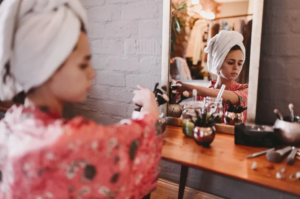 woman putting on makeup at mirror
